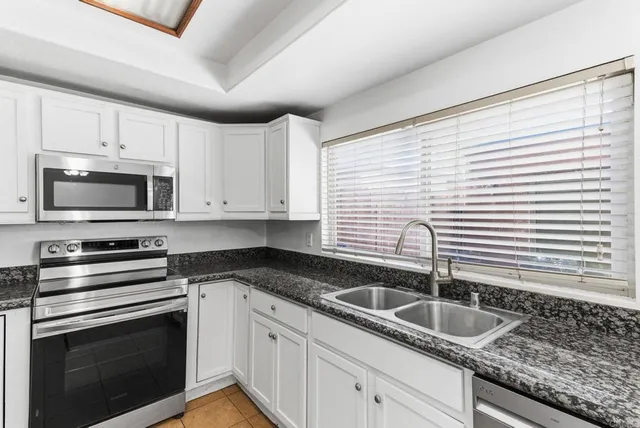 a kitchen with granite countertop white cabinets and white appliances