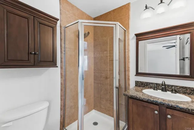 a bathroom with a granite countertop sink a toilet and shower