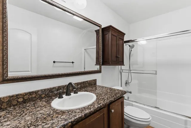 a bathroom with a granite countertop sink toilet and shower