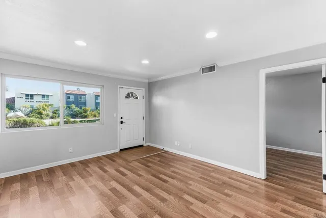 a view of an empty room with wooden floor and a window