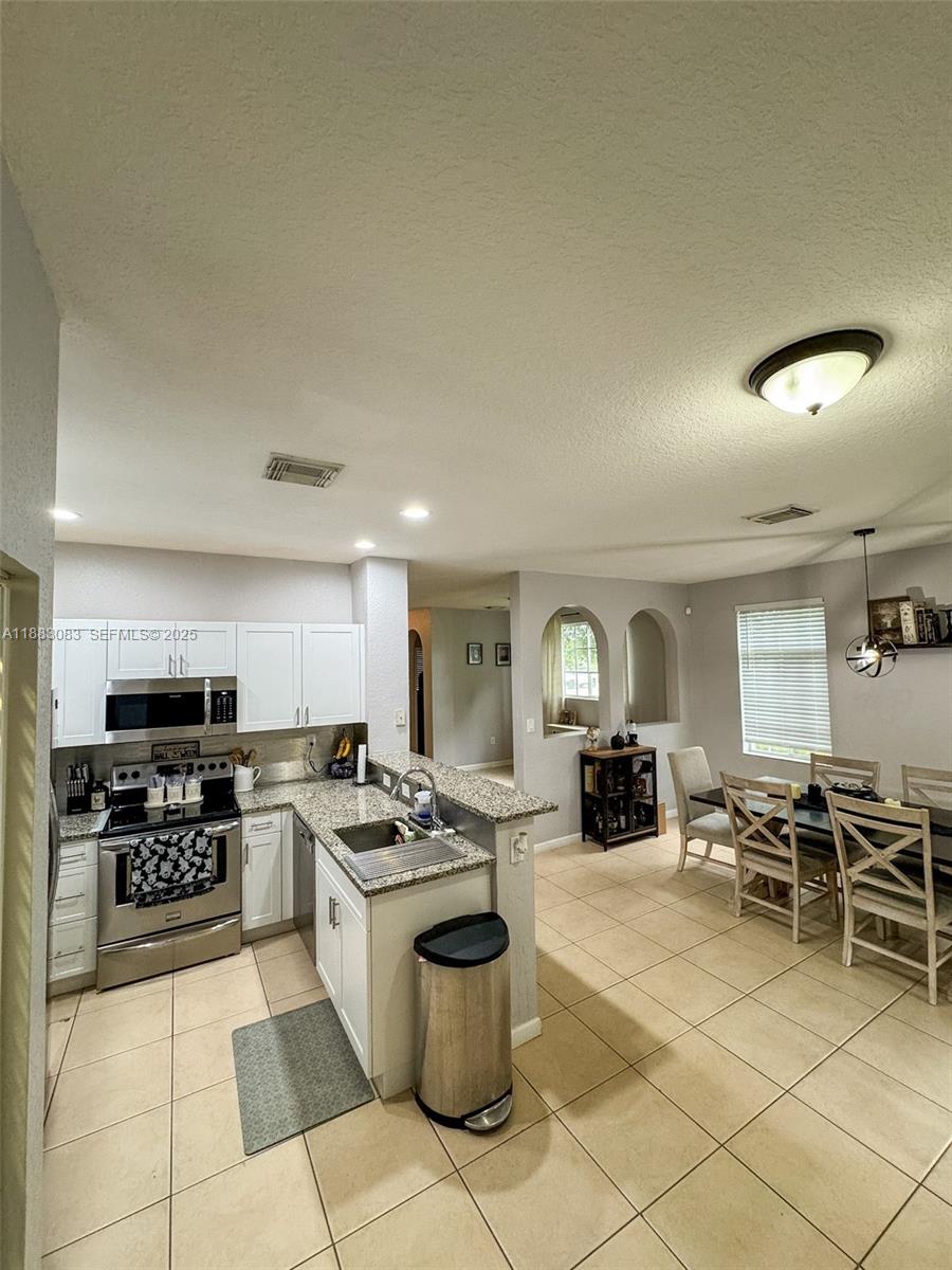 27841 Southwest 140th Avenue Homestead, FL 33032 - Photo 11 of 28 a kitchen with microwave a stove and cabinets