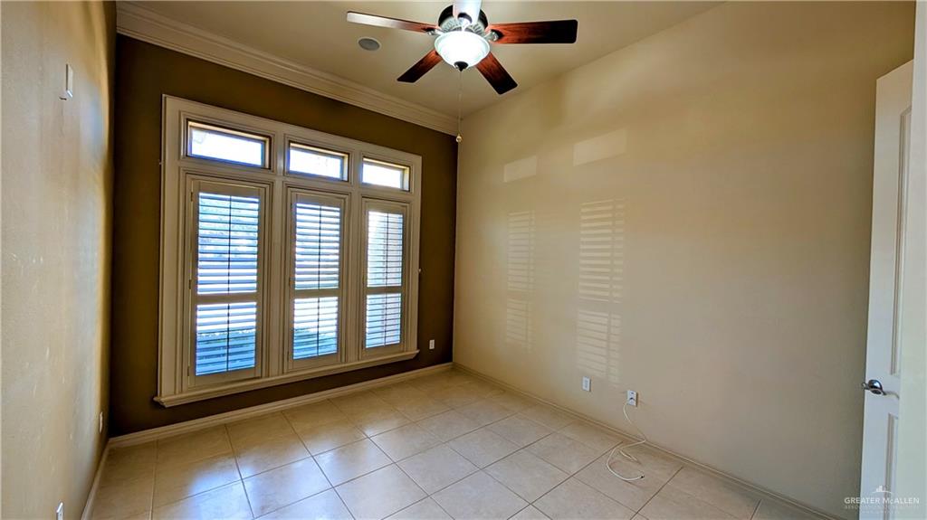 5805 Acacia Harlingen, TX 78552 - Photo 13 of 23 Unfurnished room featuring light tile patterned floors, a ceiling fan, and crown molding