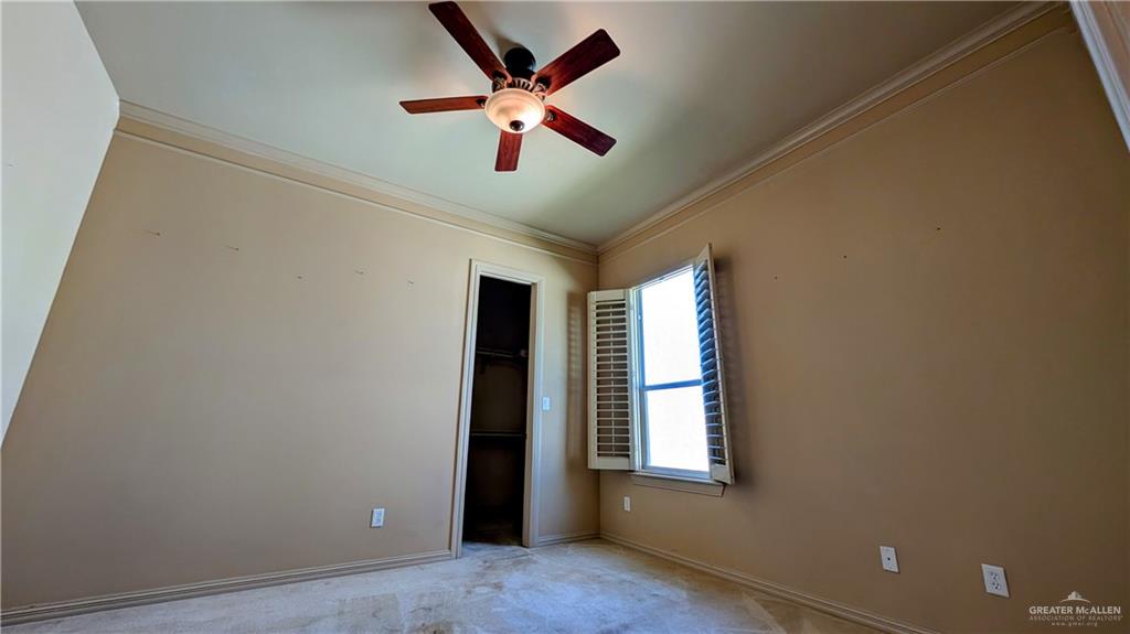 5805 Acacia Harlingen, TX 78552 - Photo 18 of 23 Unfurnished bedroom with crown molding, a spacious closet, ceiling fan, and carpet floors