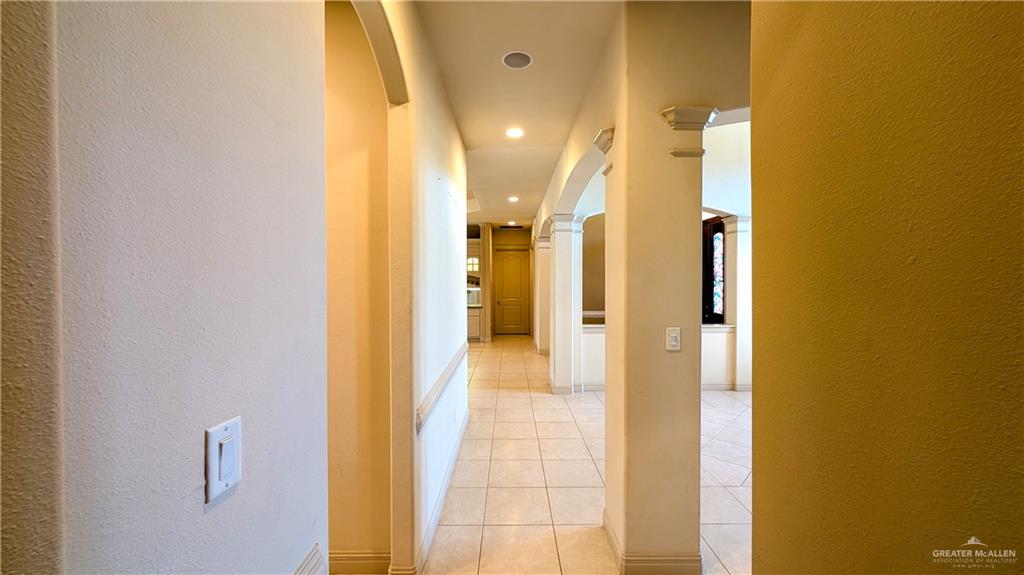 5805 Acacia Harlingen, TX 78552 - Photo 20 of 23 Hallway featuring a textured wall, arched walkways, light tile patterned floors, and recessed lighting