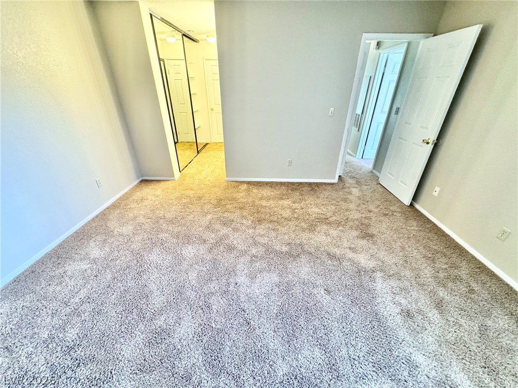 6250 West Flamingo Road, Unit 109 Las Vegas, NV 89103 - Photo 7 of 18 A spacious room offers plush carpeting and mirrored closet doors, creating an inviting atmosphere.
