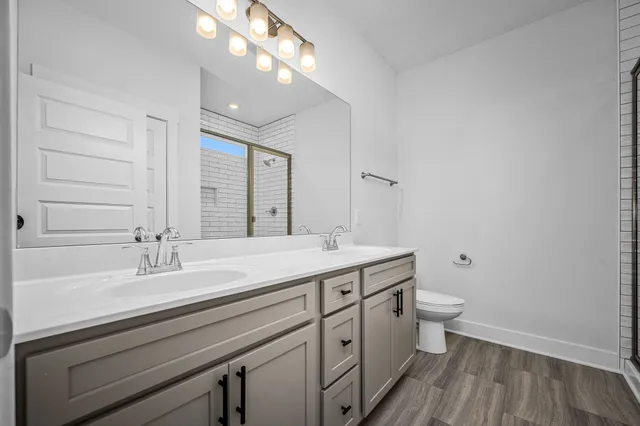 a bathroom with a sink a toilet a mirror and shower