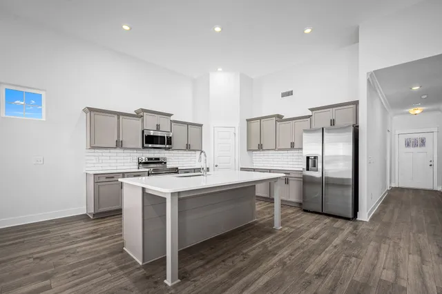 a kitchen with stainless steel appliances granite countertop a sink stove oven and white cabinets with wooden floor
