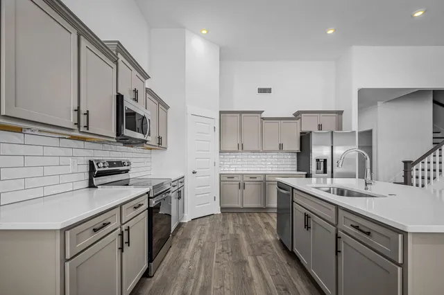 a kitchen with stainless steel appliances kitchen island granite countertop a sink stove and refrigerator