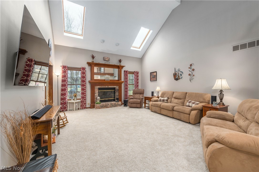 44565 Stang Road Elyria, OH 44035 - Photo 16 of 50 Living room with vaulted cathedral ceiling, dual Skylights, a brick fireplace, carpet floors, and plenty of natural woodwork and light