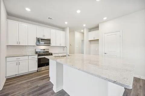519 Ridgedale Drive McKinney, TX 75071 - Photo 3 of 26 a large kitchen with stainless steel appliances granite countertop a stove a sink a refrigerator and white cabinets with wooden floor