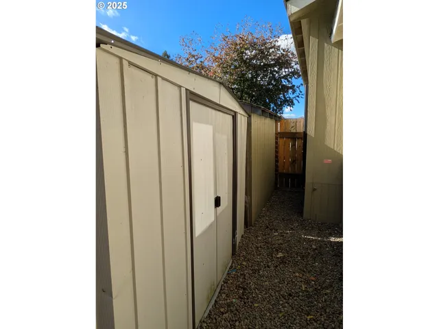a backyard of a house with wooden fence and large trees