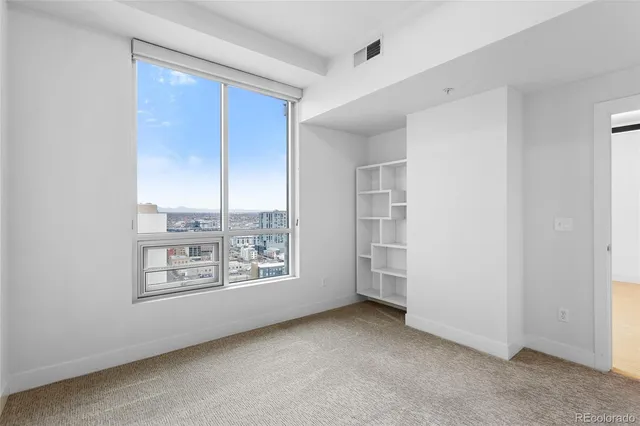an empty room with windows and cabinet