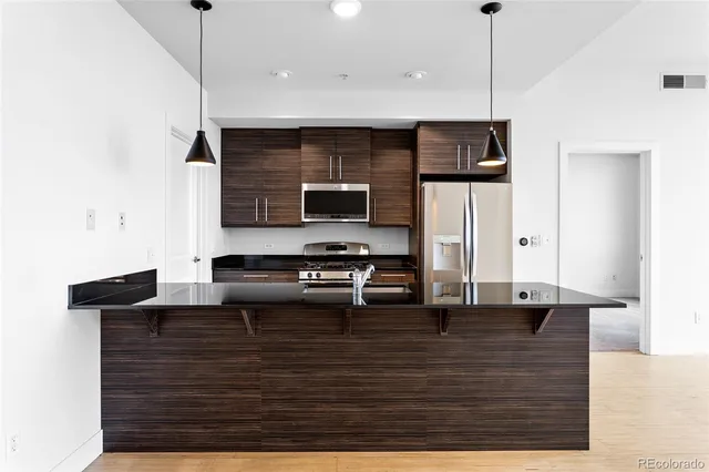 a view of kitchen with stainless steel appliances granite countertop wooden cabinets a stove top oven a sink and dishwasher