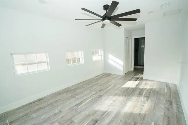 an empty room with wooden floor and windows