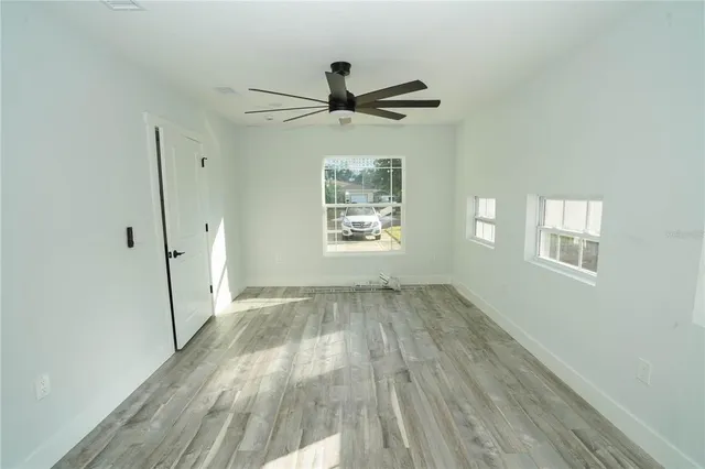 a view of empty room with wooden floor and fan