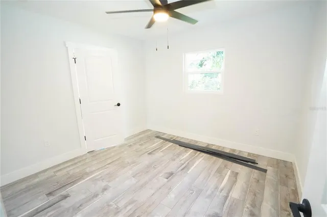 an empty room with a window and a ceiling fan