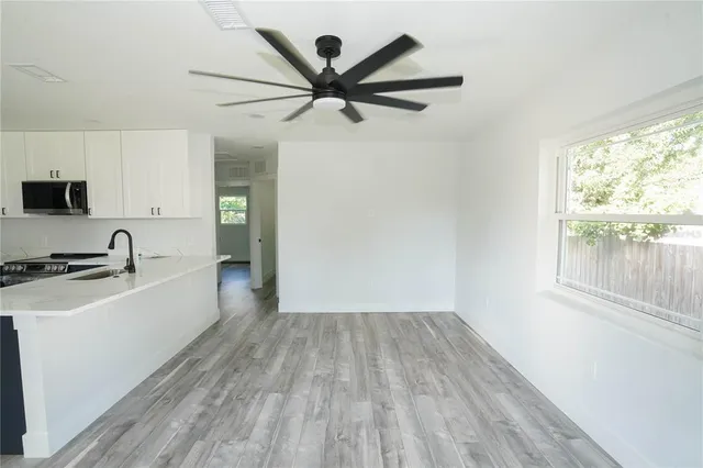 a large white kitchen with a large window a sink and stainless steel appliances