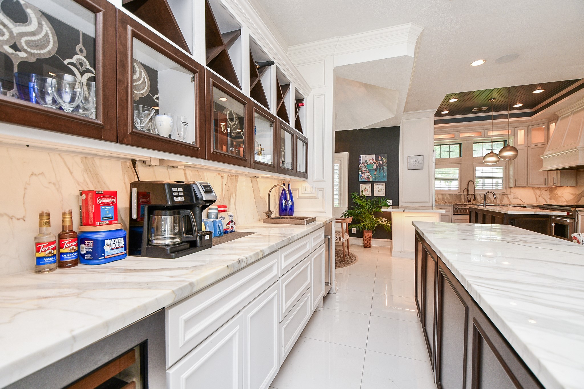 263 Wood Loop Street Houston, TX 77015 - Photo 24 of 45 This kitchen features elegant marble countertops, ample cabinet space with glass doors, and modern appliances. The layout is open and spacious, with stylish lighting and large windows that provide natural light.