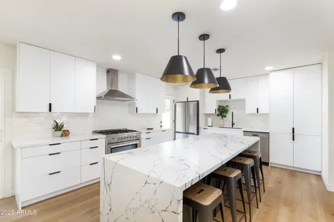 a kitchen with stainless steel appliances kitchen island a table chairs and wooden floor