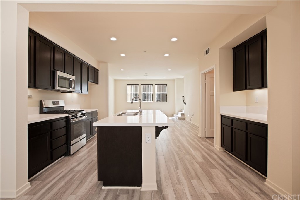 13264 Warnick Way Sylmar, CA 91342 - Photo 1 of 1 a large kitchen with stainless steel appliances a stove top oven a sink dishwasher and a microwave oven with cabinets