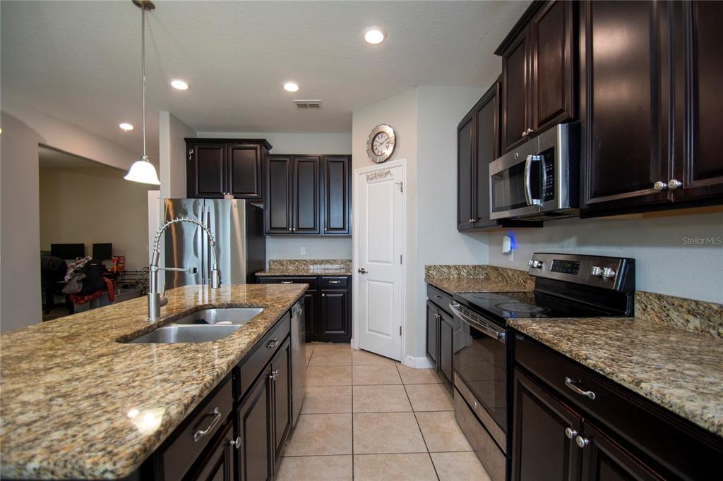 10158 Newminster Loop Ruskin, FL 33573 - Photo 5 of 12 a kitchen with granite countertop stainless steel appliances and wooden cabinets