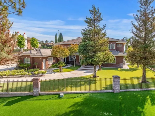 a front view of a house with a yard and a large tree