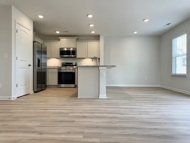 a view of kitchen with kitchen island a sink wooden floor and stainless steel appliances