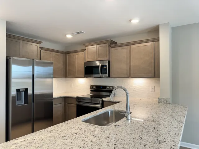 a kitchen with stainless steel appliances granite countertop a refrigerator a stove a sink and a microwave