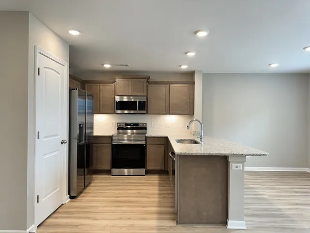 a kitchen with stainless steel appliances granite countertop a refrigerator a sink a stove and oven