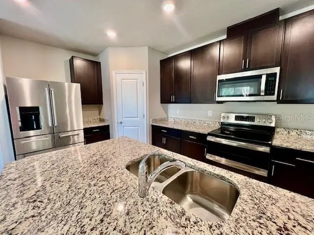 a kitchen with stainless steel appliances kitchen island granite countertop cabinets a sink and a stove