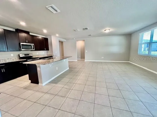 a kitchen with stainless steel appliances a sink a stove a microwave a counter top space cabinets and a window