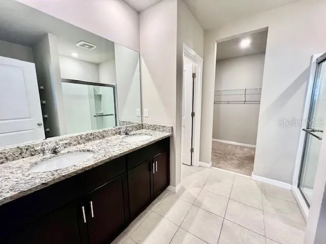 a bathroom with a granite countertop sink a mirror and a shower