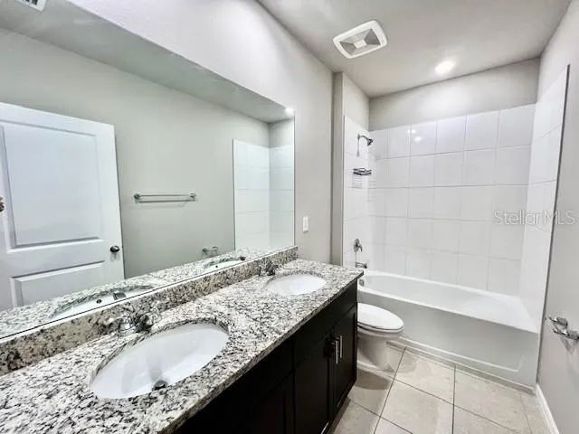 a bathroom with a granite countertop bathtub sink double and mirror