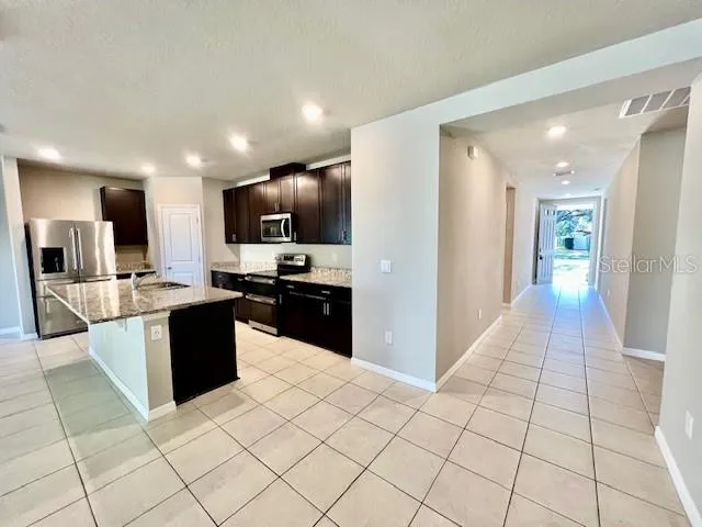 a kitchen with stainless steel appliances kitchen island granite countertop a refrigerator and a sink