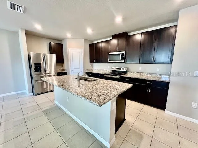a kitchen with stainless steel appliances kitchen island granite countertop a sink stove and refrigerator