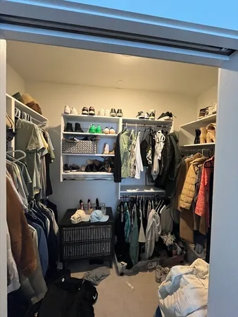 a view of walk in closet with clothes and shoes