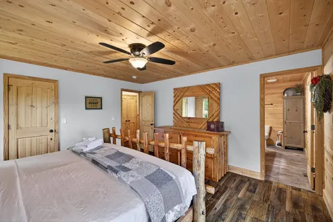 a bedroom with a bed ceiling fan and a wooden floor