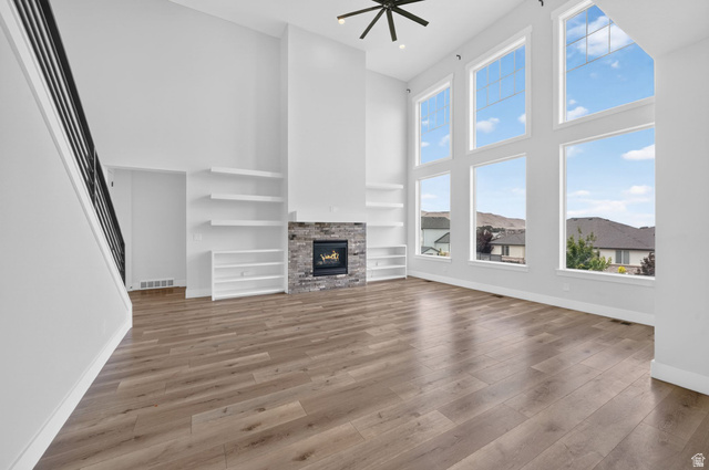 1002 West Temple Rim Lane Payson, UT 84651 - Photo 12 of 68 Spacious living area featuring a dramatic two-story ceiling, a stone-clad fireplace, and extensive wood-finish flooring