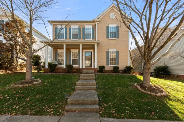 a front view of a house with a yard and trees
