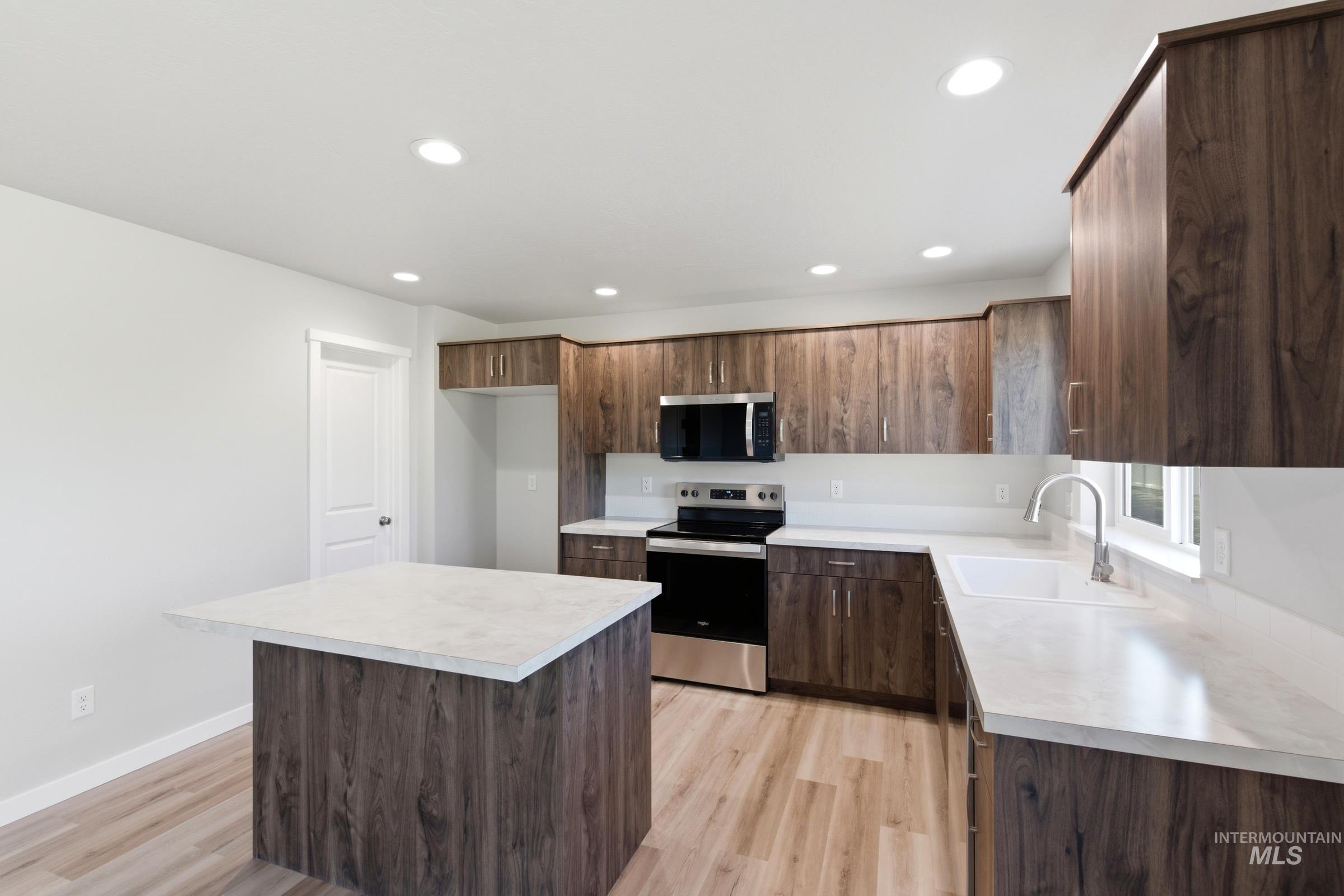 13709 Redway Court Caldwell, ID 83607 - Photo 5 of 28 Modern kitchen featuring wood-finish cabinetry, white countertops, and stainless steel appliances