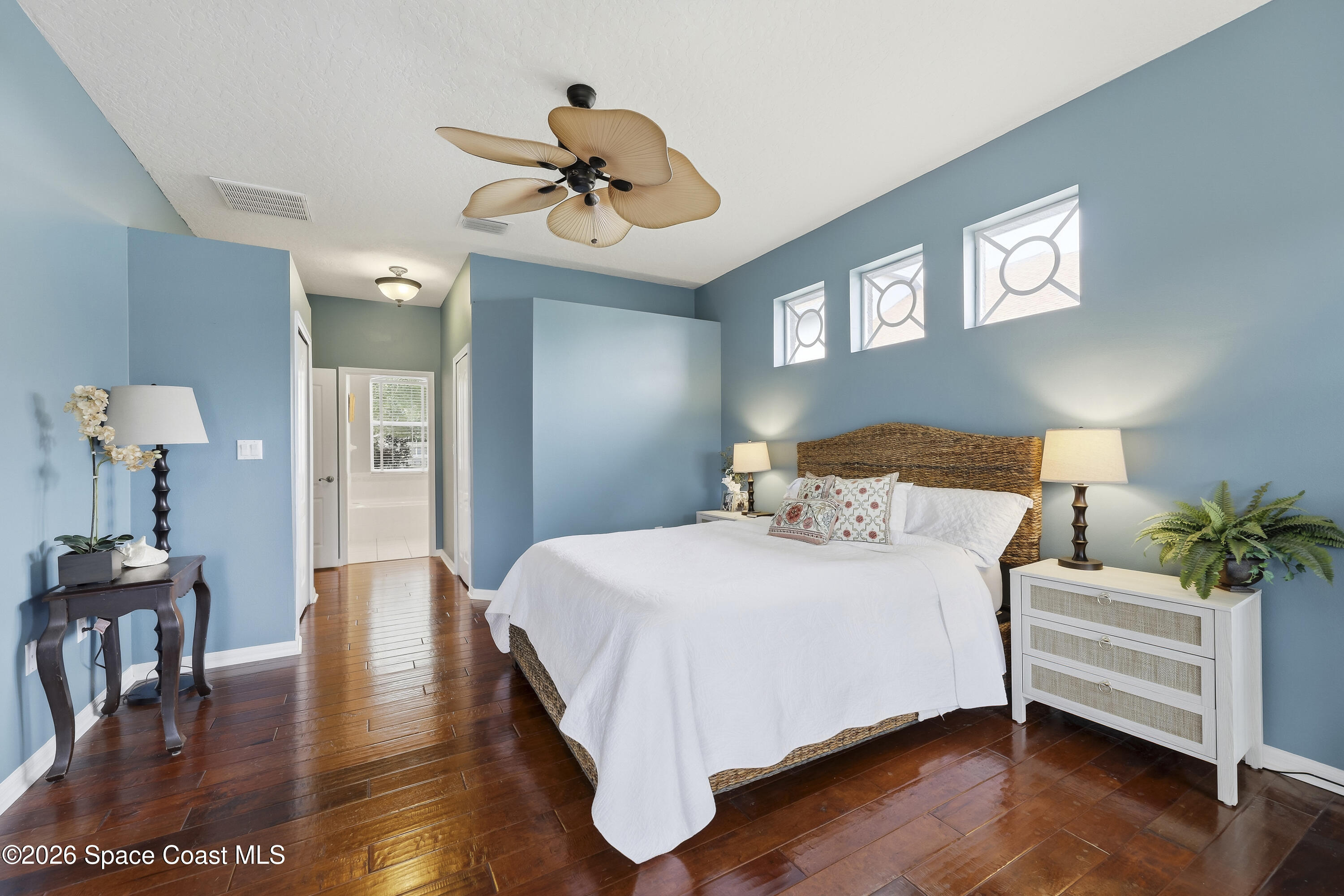 1643 Long Pine Road Melbourne, FL 32940 - Photo 28 of 63 a bedroom with a large bed wooden floor and a chandelier