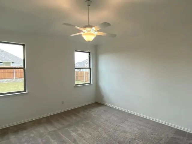an empty room with windows and fan