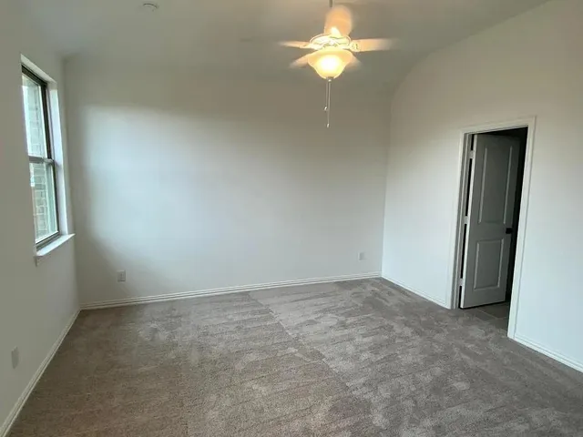 an empty room with a chandelier fan and window