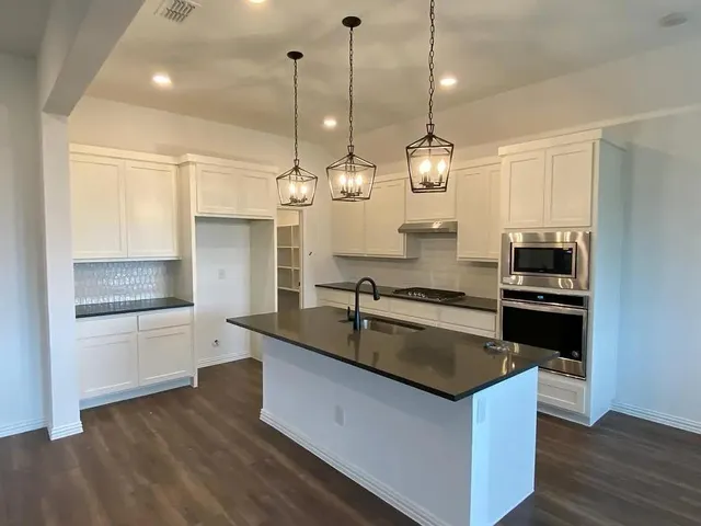 a kitchen with kitchen island granite countertop stainless steel appliances a stove a sink a center island and cabinets