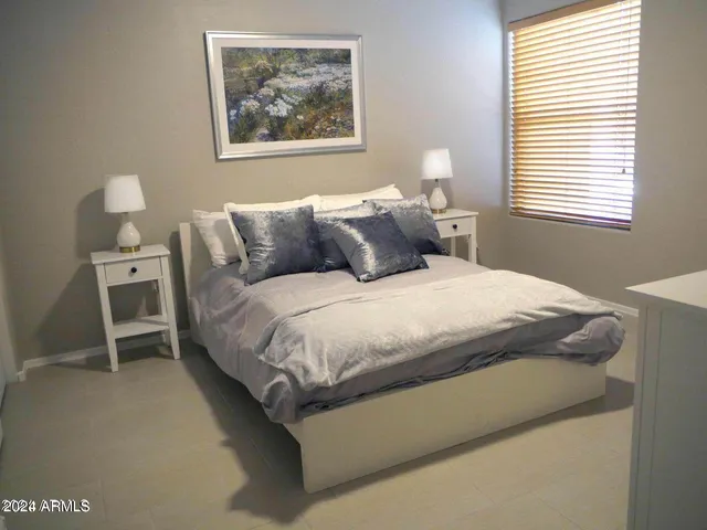 a bedroom with a bed painting on wall and a window