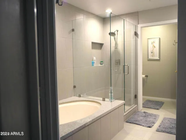 a bathroom with a granite countertop tub sink shower and mirror
