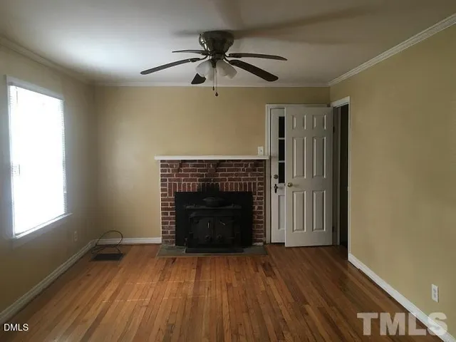 an empty room with wooden floor a fireplace and windows