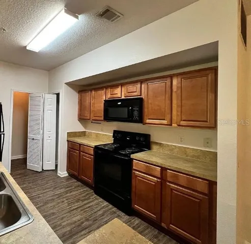 a kitchen with granite countertop a sink stove and refrigerator