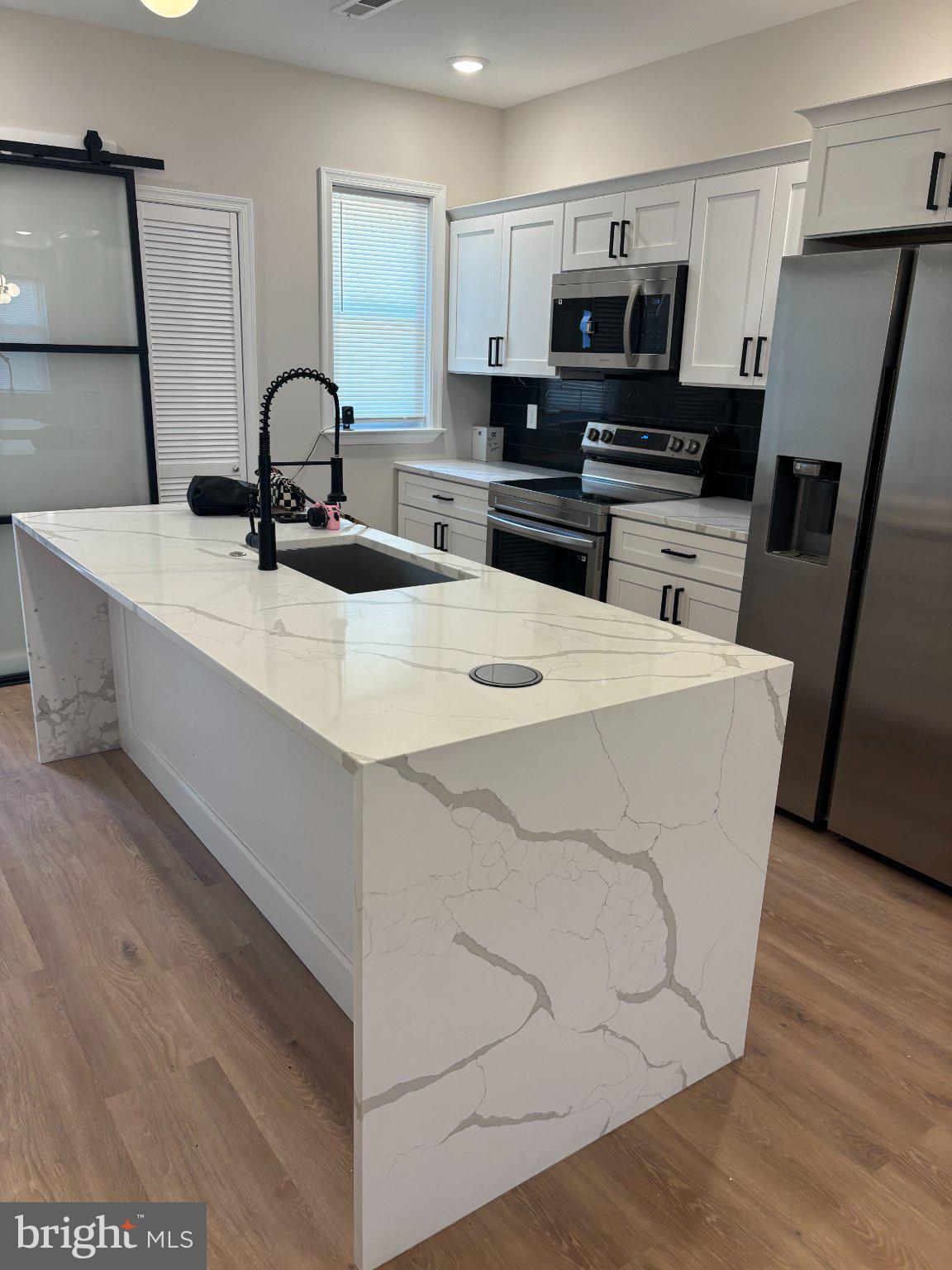 4818 Pimlico Road Baltimore, MD 21215 - Photo 17 of 18 a kitchen with a sink a microwave a refrigerator and cabinets