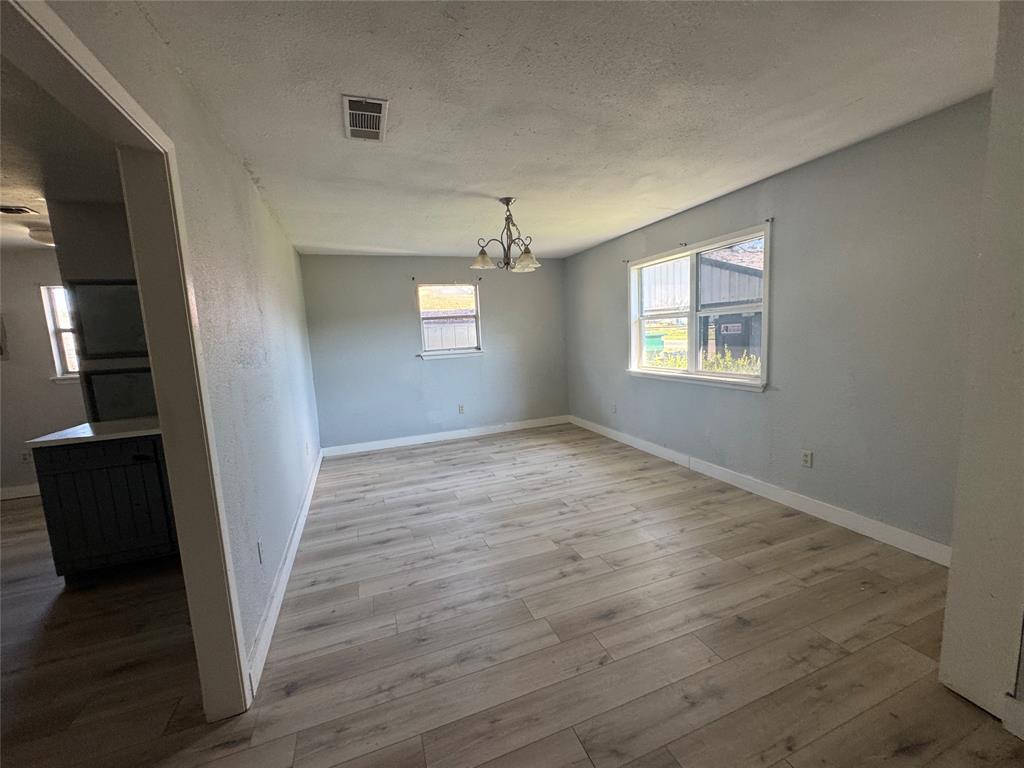 402 North Hughes Street Howe, TX 75459 - Photo 15 of 17 Unfurnished dining area featuring a chandelier, a textured ceiling, light wood-type flooring, and a textured wall